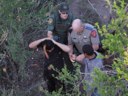 A Texas state trooper and a U.S. Border Patrol agent detain undocumented immigrants on Oct