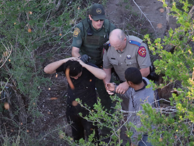A Texas state trooper and a U.S. Border Patrol agent detain undocumented immigrants on Oct