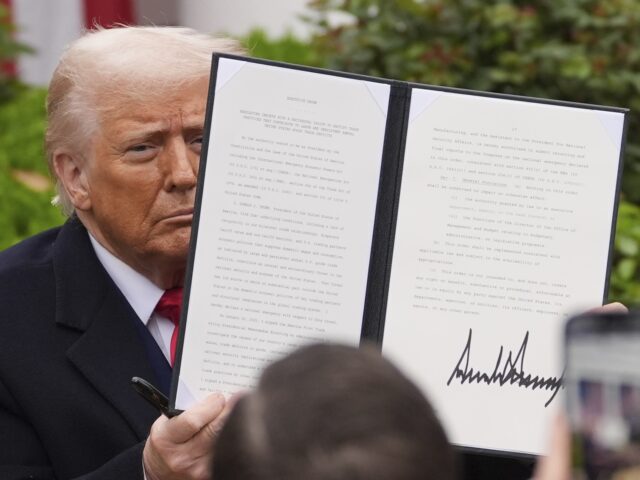 President Donald Trump holds a signed executive order during an event to announce new tari