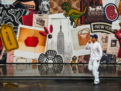 A man walks past a construction barrier outside a Coach store under renovation, decorated