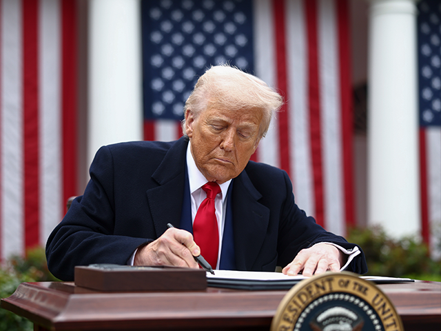 President Donald Trump signs an executive order during a tariff announcement in the Rose G