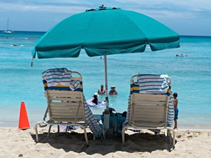 Two beach chairs are visible under an umbrella at Waikiki Beac, island of Oahu, Honolulu,