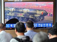 People watch a television screen showing a news broadcast with an image of a North Korean