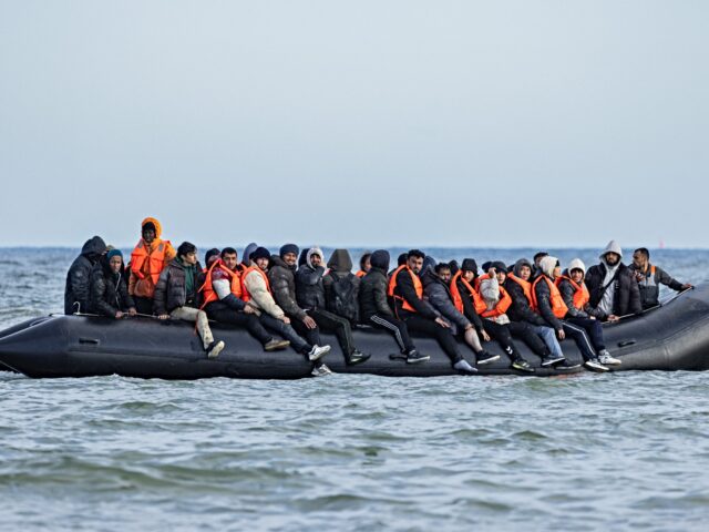 Migrants board a smuggler's boat in an attempt to cross the English Channel, off the beach