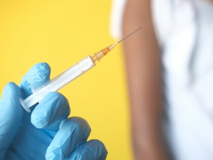 A person in blue gloves holding a syringe