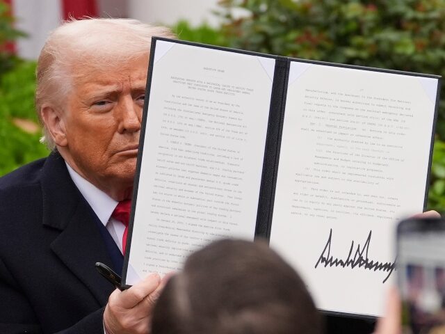 President Donald Trump holds a signed executive order during an event to announce new tari