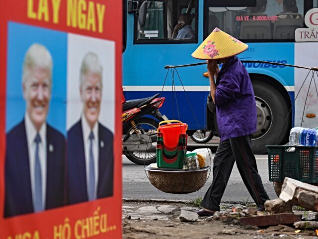 vietnam A man rides his bicycle past a billboard of a photo studio featuring an image of US Presid