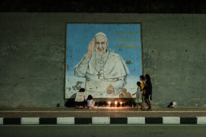 Catholics in East Timor mourn Pope Francis with candles in front of a mural near where the