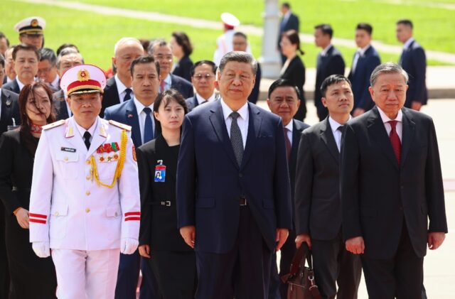 Chinese President Xi Jinping (C) walks with Vietnam's Communist Party General Secretary To