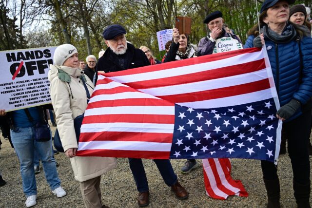 Demonstrators hold an upside-down US flag during a 'Hands Off! rally against US President