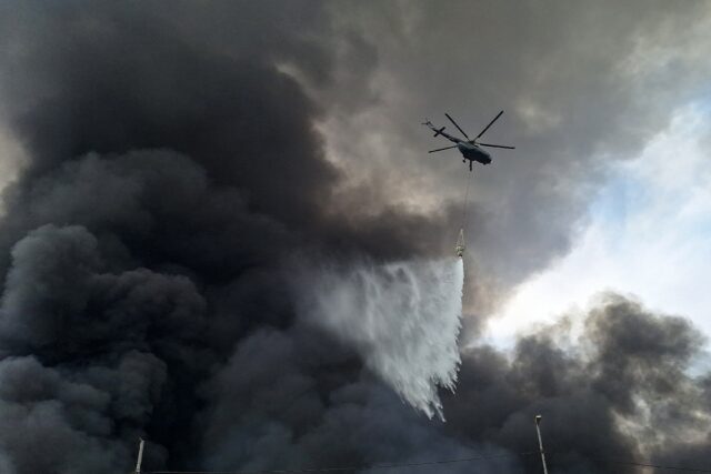 A helicopter sprays water one day after a deadly explosion at Iran's Shahid Rajaee Port