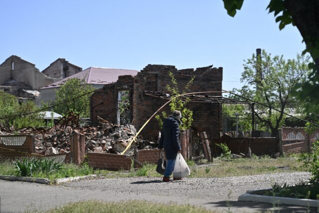 A local resident walks past a destroyed house in the town of Lyman, near the frontline in