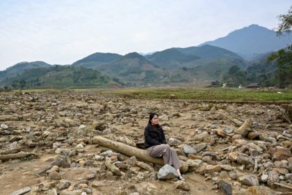 Nguyen Thi Kim sitting on a pillar of a destroyed house at the original site of Lang Nu vi