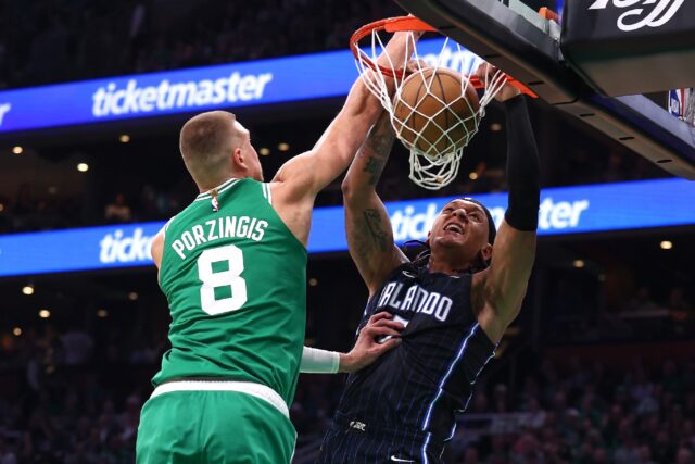 Paolo Banchero of the Orlando Magic dunks the ball against Kristaps Porzingis in the Magic