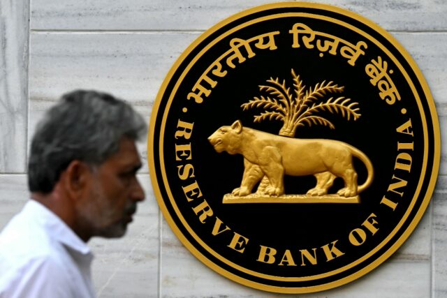 A pedestrian walks past the Reserve Bank of India (RBI) logo outside its headquarters in M