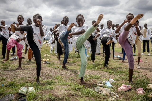 Young refugee girls practice taekwondo kicks as they warm up for a recent performance in K