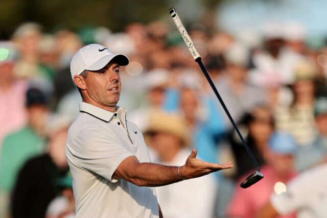 Rory McIlroy of Northern Ireland throws and catches his putter on the 18th green after fir