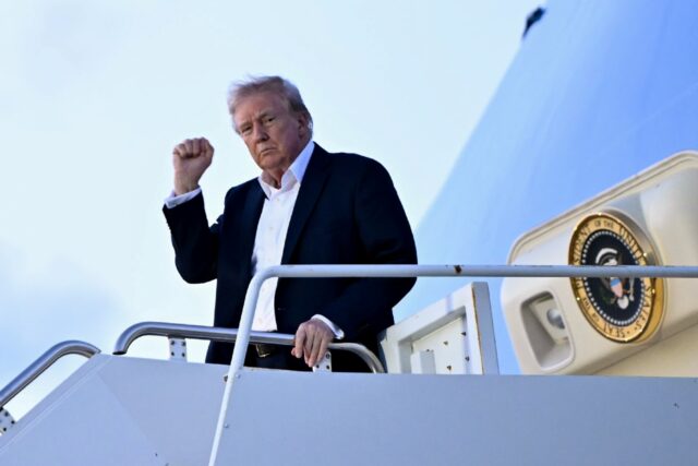 US President Donald Trump raises a fist as he steps off Air Force One at Palm Beach Intern