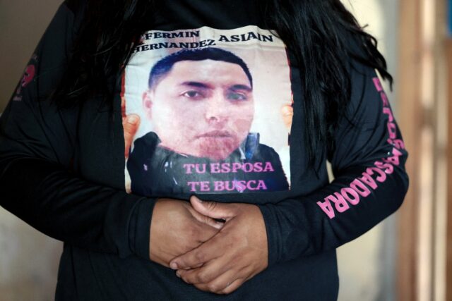 "Your wife is looking for you" reads a message worn by Rubi Cruz, whose husband is one of