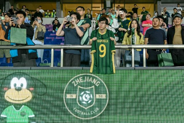 A Zhejiang FC fan holds up a shirt of Aaron Boupendza, the Gabon international footballer