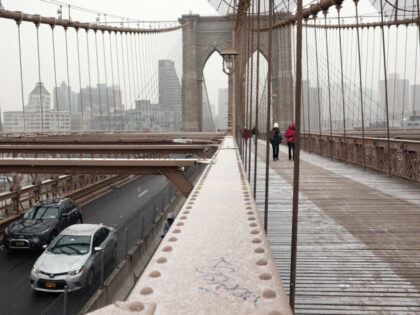 People walk along the Brooklyn Bridge as cars drive into Manhattan on January 06, 2025 in