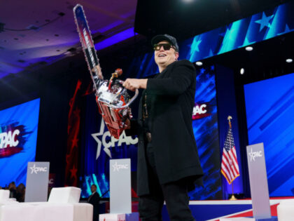Elon Musk, chief executive officer of Tesla Inc., holds a chainsaw gifted to him by Javier