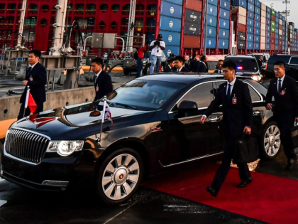 Members of China's security service run next to the car of China's President Xi Jinping, a
