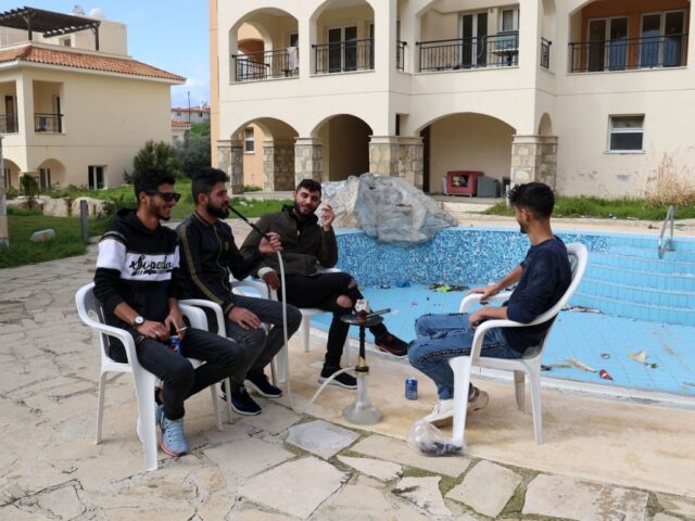 Syrian refugees sit by an empty pool at the Saint Nicolas residential complex, where aroun