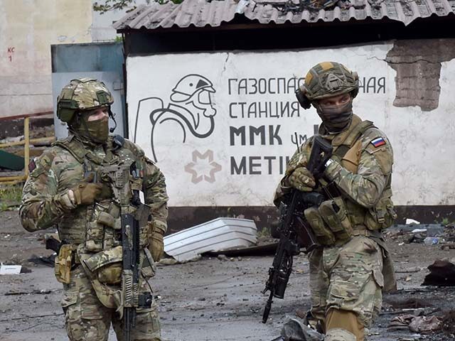 Russian servicemen stand guard at the destroyed part of the Ilyich Iron and Steel Works in