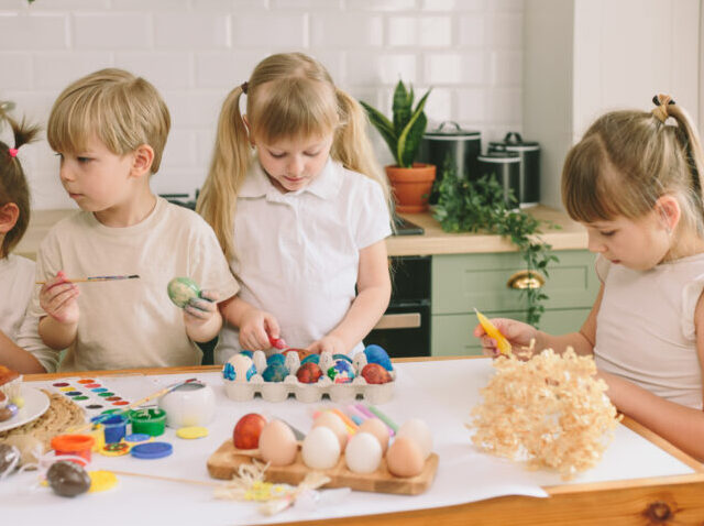 Kids painting eggs and Easter bread in the kitchen
