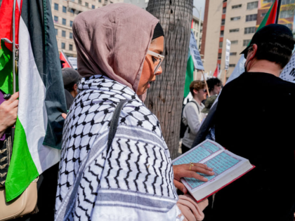 A Muslim woman reads the Quran as pro-Palestine protesters demonstrate against the arrest