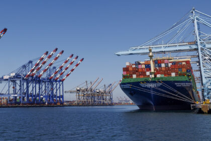 LOS ANGELES, CA - MAY 9, 202: Cargo is loaded onto a container ship on the right while the