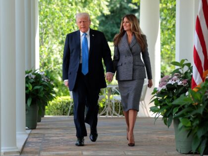Melania Trump smiles walking with President Donald Trump