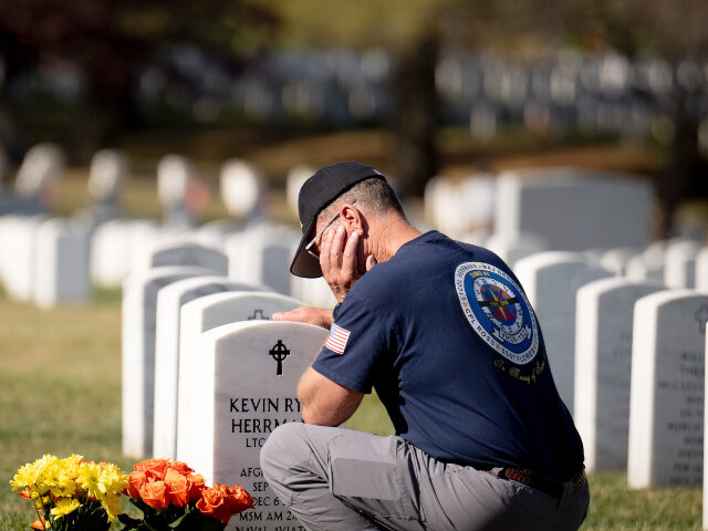 Kevin Herrmann, a retired Marine Corps Col., kneels at the grave of his son, Lt. Col. Kevi