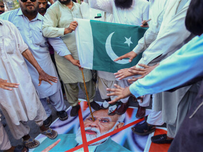 Supporters of Pakistan Sunni Tehreek stand on a photo of Indian Prime Minister Narendra Mo