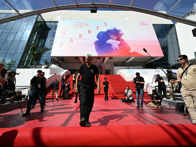 An employee (C) unrolls the red carpet at the Palais des Festivals ahead of the opening ce