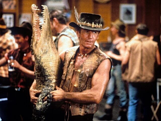 Paul Hogan carrying dead crocodile in bar in a scene from the film 'Crocodile Dundee', 198