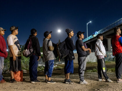 EAGLE PASS, TEXAS - SEPTEMBER 29: Under a full moon Venezuelan immigrants stand in line to