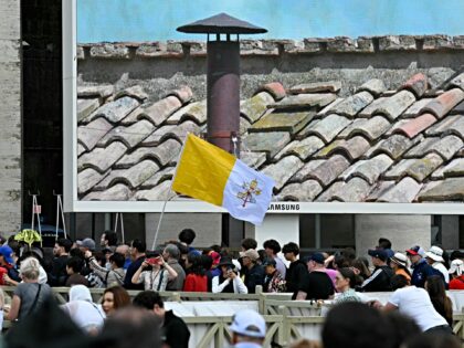 A person walks with a Vatican's flag in St Peter's square on the second day of the conclav