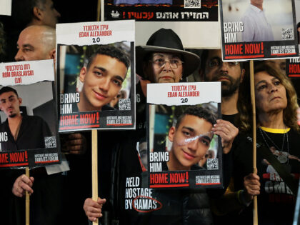 TOPSHOT - Relatives and supporters hold placards bearing portraits of Israeli hostages hel
