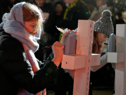 Supporters sign crosses during a candlelight vigil Tuesday, Dec. 17, 2024, outside the Wis