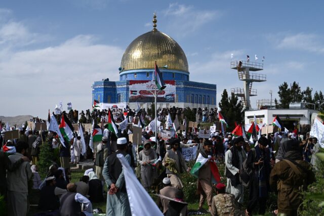 Afghan men holding Taliban flags and Palestinian national flags take part in an anti-Israe