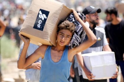 A boy carries a box of supplies from the Gaza Humanitarian Foundation, a private US-backed
