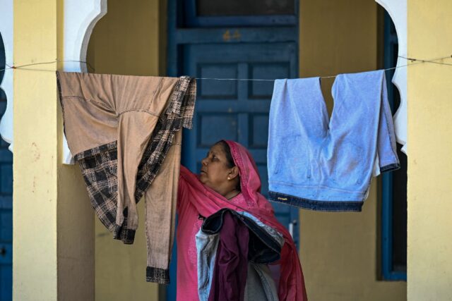 A displaced woman hangs clothes to dry at a Sikh temple in Jammu, a key city in Indian-adm