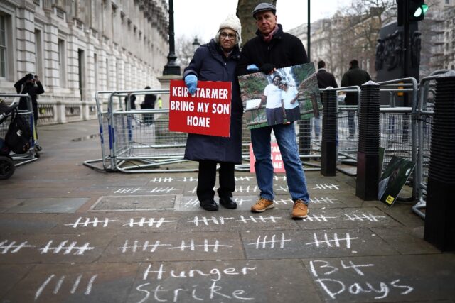 Fattah's mother Soueif (L) holds a placard reading 'Keir Starmer, bring my son home'