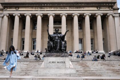 Flanking a famous Alma Mater statue, students sit on the steps of the Low Memorial Library