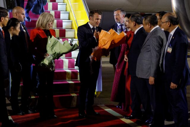France's President Emmanuel Macron (C) and his wife Brigitte Macron (in red) are greeted b