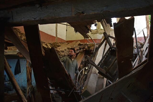 A man in Jura village in the Neelum Valley inspects his damaged home after the latest Indi
