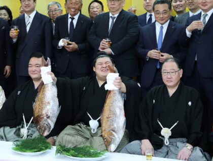 Onosato (centre) holds up a fish as to celebrate being promoted to sumo "yokozuna" or gran