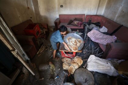 A Palestinian boy salvages bread from a makeshift bakery hit by Israeli strikes at the Nus